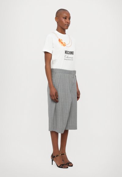White short-sleeve t-shirt with graphic print and text, paired with gray pinstriped culottes. Black strappy heels complete the outfit.