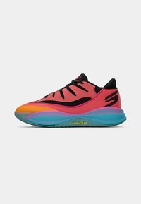 Baskets de sport rouge et orange avec des lacets noirs, logo "S" noir et semelle épaisse dégradée bleu-violet portant la mention "Goodyear".