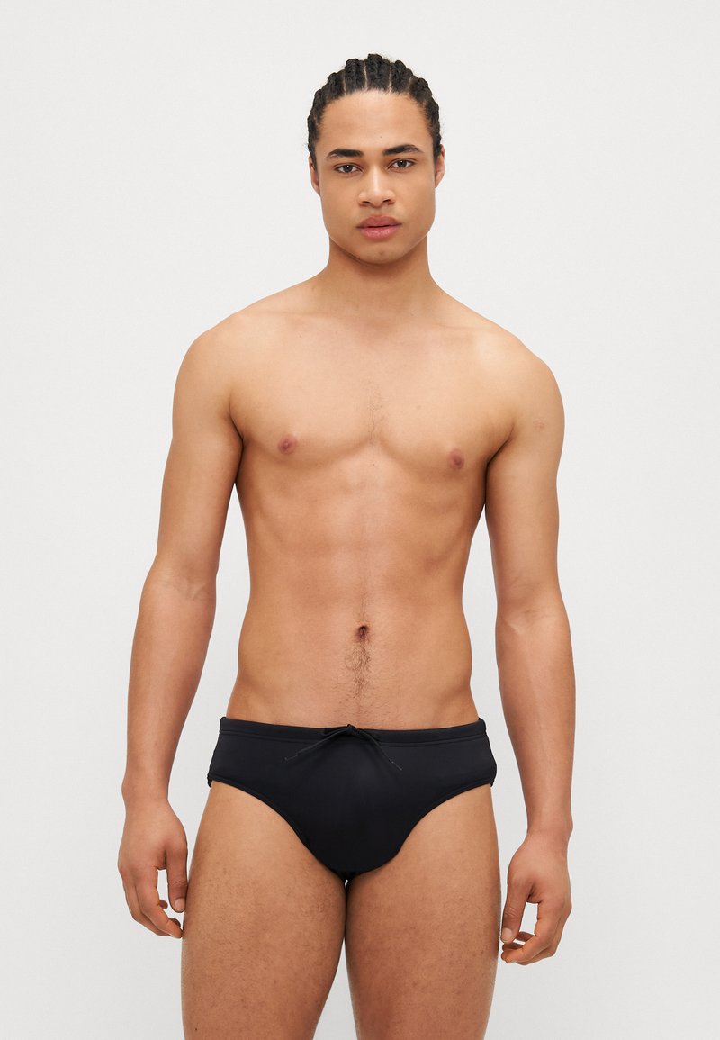 Schwarze Schwimmshorts mit Kordelzugbund, aus elastischem Material, mit glatter Textur und tailliertem Schnitt.