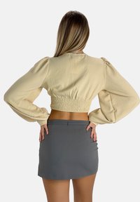 Beige kort topp med puffärmar och elastisk midja, kombinerad med en grå figursydd kort kjol. Slätt tyg och skräddarsydd design.