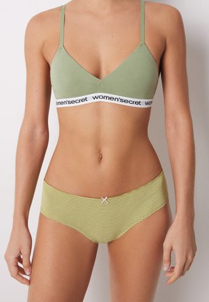 Bralette in cotone verde chiaro con spalline regolabili, con una fascia nera etichettata "women's secret." Mutande hipster a righe verdi abbinate con un piccolo fiocco.