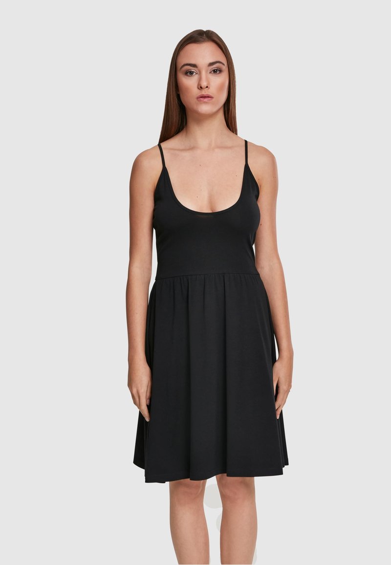 Robe noire sans manches avec un décolleté en cœur profond, un corsage ajusté et une jupe évasée, fabriquée en tissu doux au toucher lisse.