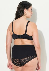 Zwarte bralette met verstelbare bandjes en haaksluiting; hooggesneden zwarte onderbroek met kantaccenten en bloemenpatronen.