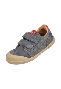 Zapato de ante gris con dos correas de velcro, forro interior color tostado, suela de goma beige y pequeñas perforaciones en el lateral para transpirabilidad.