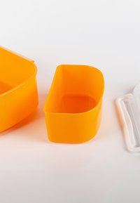 Orange plastic storage containers in various sizes; one is oval and larger, another is rectangular and smaller, both with smooth surfaces.
