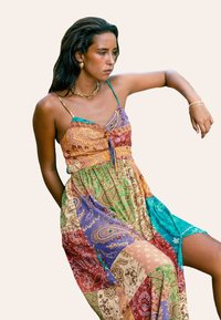 Vestido de patchwork multicolorido que presenta una mezcla de patrones paisley y florales. Tirantes estilo espagueti con un cuerpo ajustado y una falda fluida.