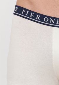 Fehér pamut boxer alsónadrág sötétkék derékrésszel, amelyen fehér betűkkel szerepel a "PIER ONE" felirat és kontrasztos vonal részletek találhatóak.