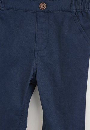 Dunkelblaue Hosen mit strukturierter Oberfläche, ausgestattet mit einem braunen Knopf und elastischem Bund, seitlichen Taschen und gesteppten Details.