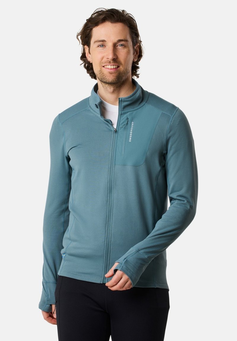 Vaaleansininen vetoketjulla suljettava takki, joka on valmistettu teksturoidusta kankaasta. Mallissa on seisova kaulus ja rintatasku, jossa on logoyksityiskohta. Pitkät hihat, joissa on peukaloaukot.