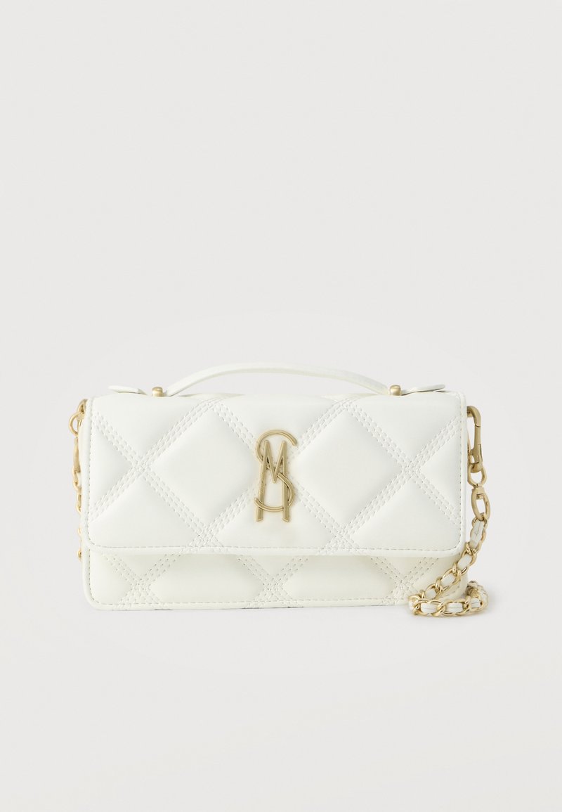 Λευκή καπιτονέ τσάντα χειρός με χρυσή αλυσίδα και χρυσλό μονογράμμα λογότυπο στο εμπρός καπάκι, τοποθετημένη σε απλό φωτεινό φόντο.