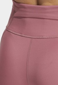 Højtaljede lyserøde leggings lavet af glat, strækbart stof. Har kontrasterende syninger og en sømløs talje for komfort.