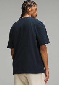 Tricou de bumbac cu mânecă scurtă, de culoare bleumarin, cu croi lejer și decolteu rotund, având o textură netedă și fără modele vizibile.