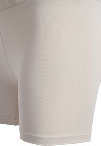 Pantaloni sportivi beige realizzati in un tessuto liscio ed elastico. Presentano un design aderente con una vita elasticizzata e cuciture piatte per un maggiore comfort.