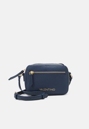 Sac bandoulière en cuir bleu marine à finition texturée, avec fermeture éclair dorée et logo. Comprend une bandoulière amovible et une poche zippée extérieure.