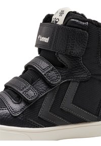 Sneakers alte nere in pelle testurizzata, con due cinturini in Velcro e accenti a chevron grigi a contrasto sui lati. Suola in gomma bianca.