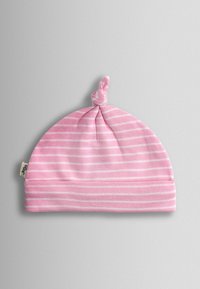 Bonnet pour bébé rayé rose et blanc avec un nœud plat sur le dessus et une petite étiquette en tissu sur le côté, sur un fond gris uni.