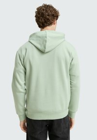 Felpa verde menta con cappuccio regolabile, polsini e orlo a coste, realizzata in tessuto liscio. Caratterizzata da un design semplice senza motivi visibili.