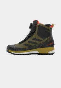 Półwysokie buty hikingowe w oliwkowym kolorze z czarnymi akcentami, z teksturowaną cholewką, wzorzystymi bokami i jaskrawoczerwonym kołnierzem.