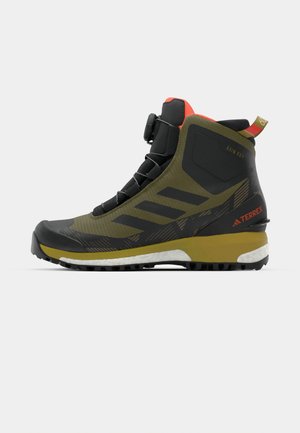 Mid-Cut Wanderstiefel in Olivgrün mit schwarzen Akzenten, ausgestattet mit einem strukturierten Obermaterial, gemusterten Seiten und einem leuchtend roten Kragen.