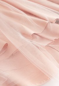 Blødt lyserødt transparent tylstof med fin netstruktur, blidt draperet i sarte, flydende folder.