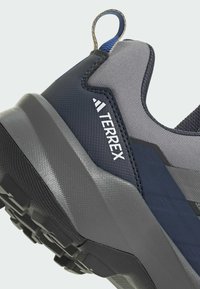 Grau und marineblaue Outdoor-Schuhe mit strukturiertem Obermaterial, Gummisohle und verstärktem Absatz. Mit erhöhtem Logo und Zugschlaufe für einfaches Anziehen.
