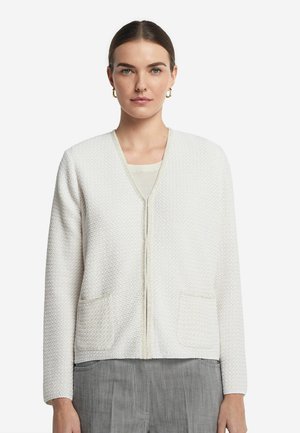 Vit strukturerad cardigan med v-ringning, framdragkedja och två framfickor. Har ett subtilt mönster och matchande kant.