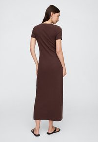 Brązowa, krótka sukienka maxi z krótkim rękawem o dopasowanym kroju, wykonana z gładkiego, elastycznego materiału, sięgająca powyżej kostki.