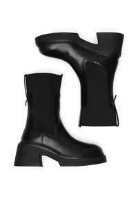 Mustad nahast pahkluu saapad elastsete külgedega, paksud kontsad ja sile tekstuur. Omavad unikaalset kuju ja minimalistlikku disaini.