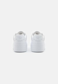 Weiße Ledersneaker mit einem gepolsterten Kragen, flachen Schnürsenkeln und einem geprägten Logo an der Ferse. Mit einer strukturierten Gummisohle für optimalen Halt.