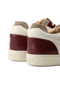 Leder- und Wildledersneaker mit einem cremefarbenen Obermaterial, burgunderfarbenen Fersenakzenten und einer strukturierten Sohle. Enthält runde Schnürsenkel und Nähedetails.