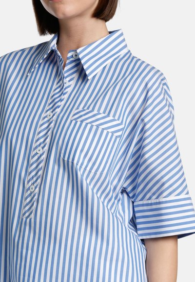 Light blue and white striped oversized shirt with a classic collar, short sleeves, and a chest pocket, made from smooth cotton fabric.
