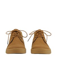 Zapatos de ante marrón con punta redondeada y suelas de goma en color tostado que contrastan. Cuentan con cordones y costuras laterales, mostrando un diseño minimalista.