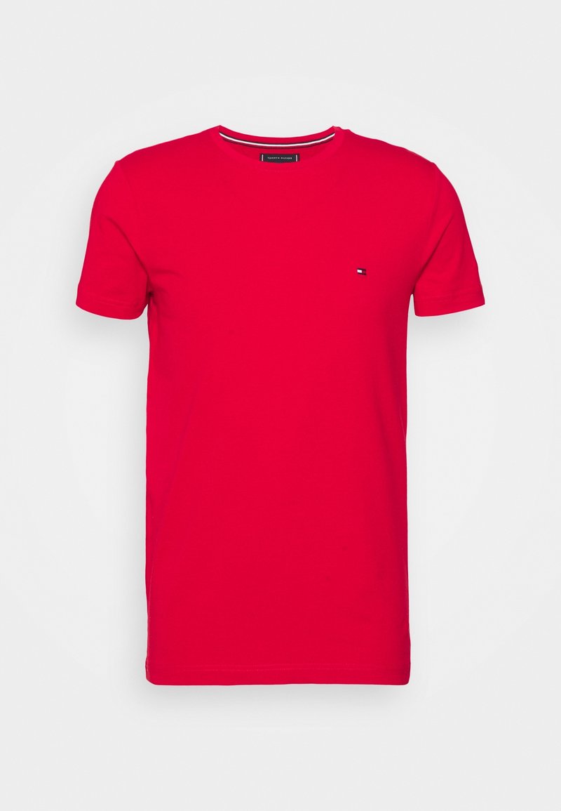 T-shirt en coton rouge avec un col rond, des manches courtes et un petit logo sur la poitrine, présentant une couleur unie et une texture lisse.