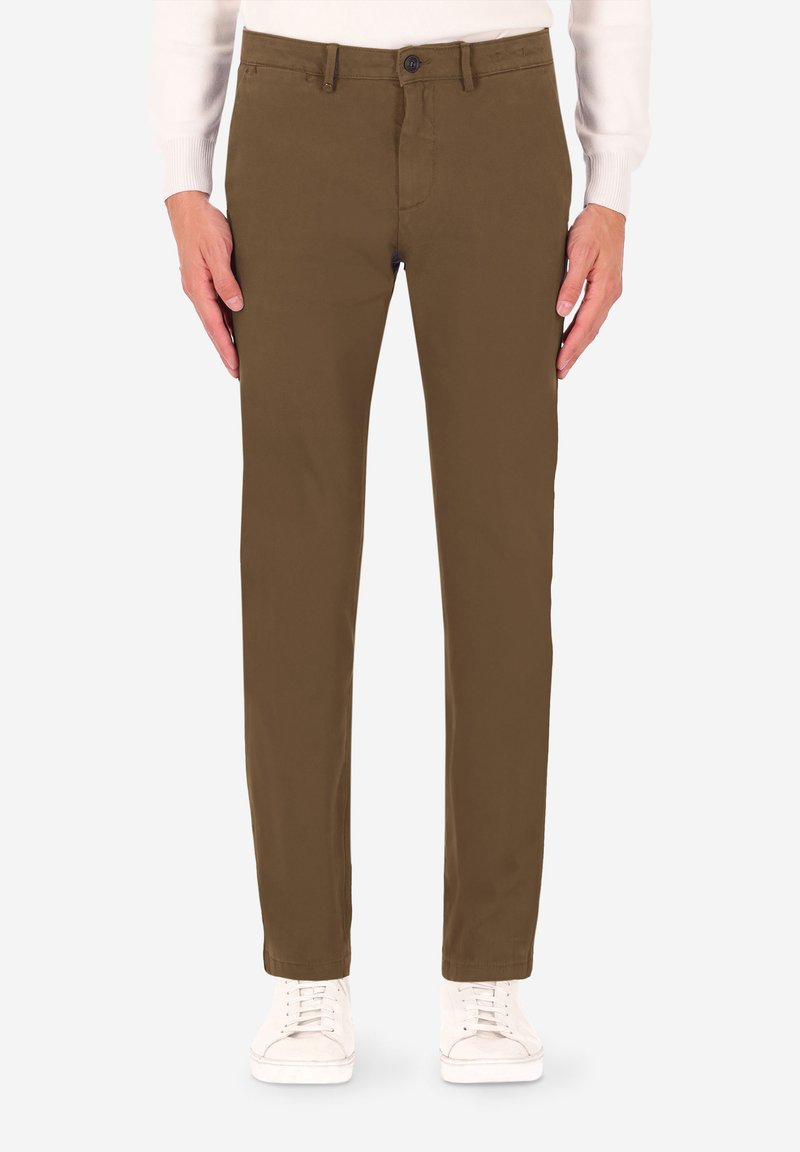 Pantaloni di cotone marroni con taglio dritto, con chiusura a bottone e tasche frontali, abbinati a sneakers bianche.