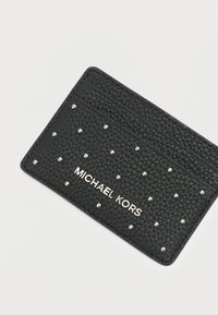 Μαύρη δερμάτινη θήκη καρτών με υφή, ασημί τρουκς και ανάγλυφο λογότυπο "MICHAEL KORS" στο μπροστινό μέρος.