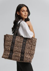 Gequilted tas met luipaardprint en zwarte "HEYMARLY" riemen. Kenmerkt zich door een zachte, gestructureerde oppervlakte en een ruime indeling om items te dragen.