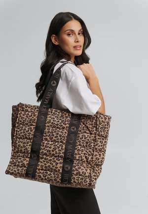 Sac fourre-tout matelassé à imprimé léopard avec des poignées noires "HEYMARLY". Présente une surface douce et texturée ainsi qu'un design spacieux pour transporter des objets.
