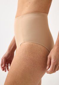 Beiga höga trosor i slät tyg med sömlös design. Midjebandet är brett och benöppningarna är skurna högt för komfort.