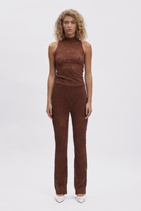 Top in pizzo marrone con collo alto abbinato a pantaloni aderenti coordinati, caratterizzati da intricati motivi a taglio e una finitura texturizzata.