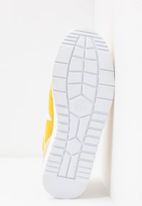 Sole of white rubber-soled sneaker with deep treads, showing UK 4.0 and EU 37.0 shoe size, against a white background.