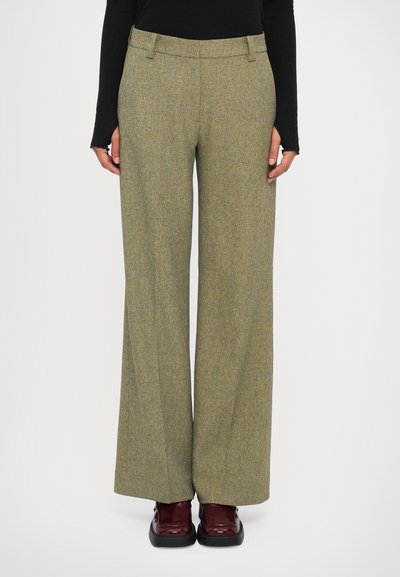 Wide-leg trousers in a textured olive green fabric with a subtle pattern. Features a fitted waistband and side pockets. Worn with dark burgundy shoes.