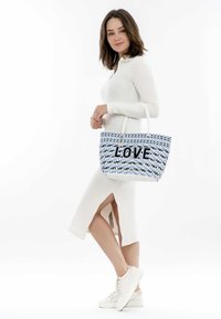 Borsa a spalla intrecciata in blu e bianco con la scritta "LOVE" in lettere nere, dotata di manici intrecciati e una superficie texturizzata, posizionata su uno sfondo semplice.