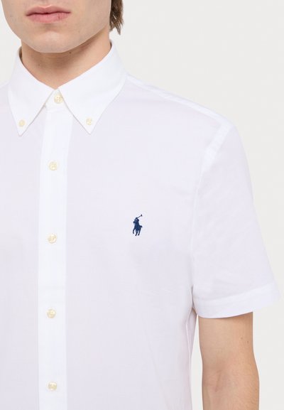 Chemise blanche à manches courtes en coton, dotée d'un col classique, de boutons en plastique et d'un petit logo polo navy sur la poitrine.
