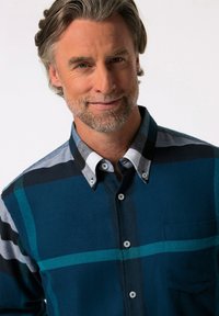 Camisa de cuadros azul con cuello abotonado, bolsillo en el pecho y patrones de cuadros en gris y negro en los hombros.