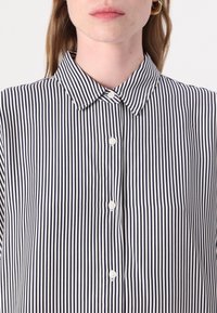 Camisa de botones con un patrón de rayas verticales en azul marino y blanco, que presenta un cuello clásico y botones blancos en la parte delantera. Textura suave.