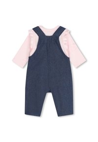 Salopette en denim bleu foncé avec une chemise à manches longues rose en dessous, présentant des manches à volants et un motif en forme de cœur.