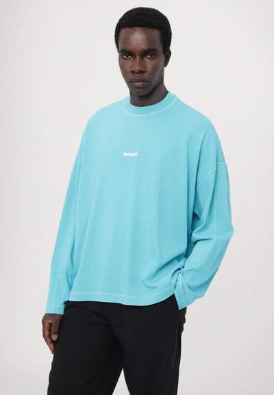 Light blue oversized sweatshirt made of cotton with a crew neck and white "BONSAI" logo on the chest, featuring dropped shoulders and stitching details.