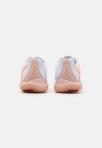 Scarpe da ginnastica bianche con accenti rosa, dotate di una suola texturizzata e un design elegante. La parola "Vantage" è ben visibile sul tallone.