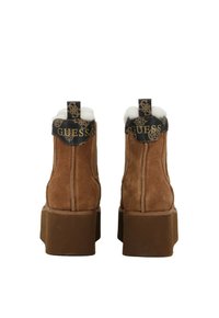 Stivaletti in suede marrone con una suola piatta spessa, dotati di fodera in pelliccia bianca e una cintura con logo in rilievo nera nella parte superiore.