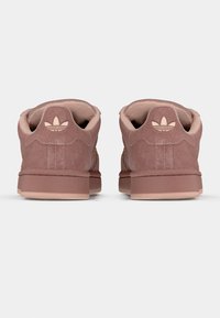 Ružové semišové tenisky s textúrovaným povrchom, vybavené jemnou podšívkou a podpisovým logom na päte. Nízky profil a plochá podrážka.